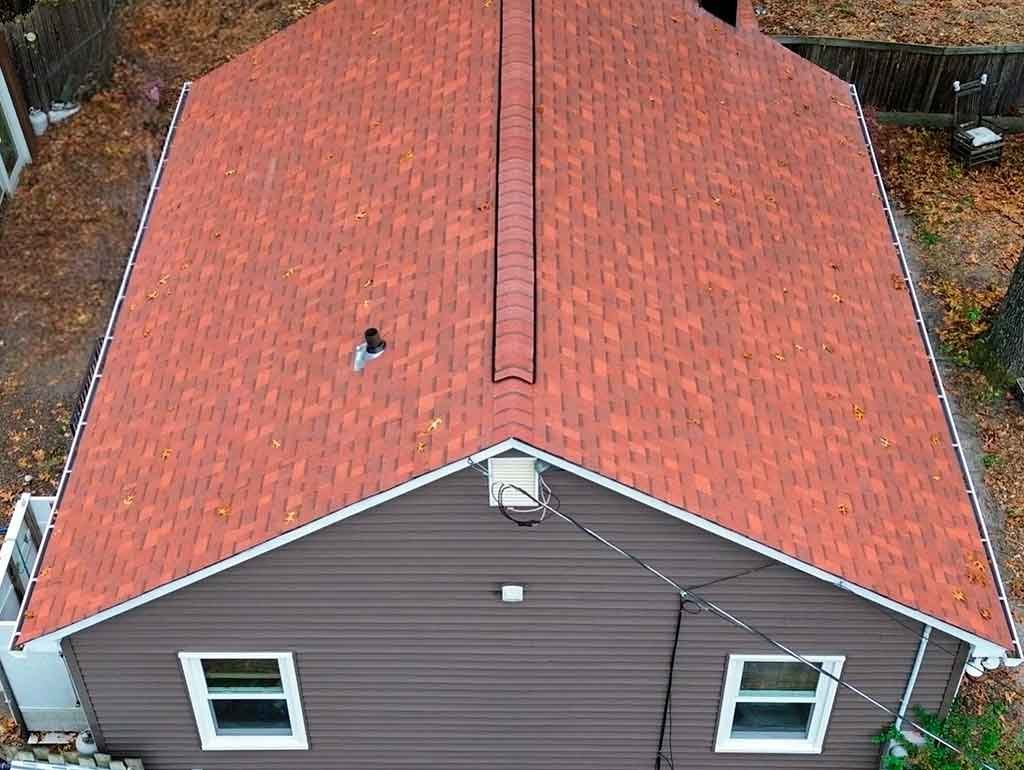 Professional roofer repairing damaged asphalt shingles on a residential roof.